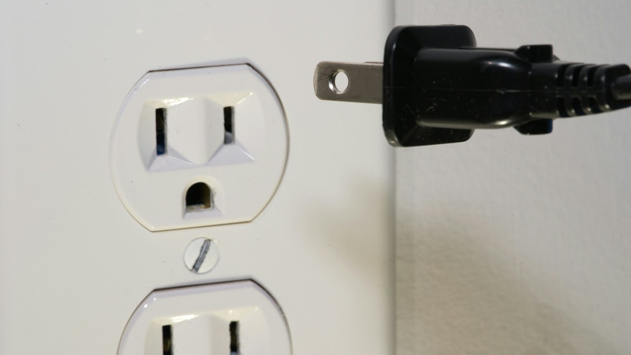 A power plug pulled out of a wall outlet.